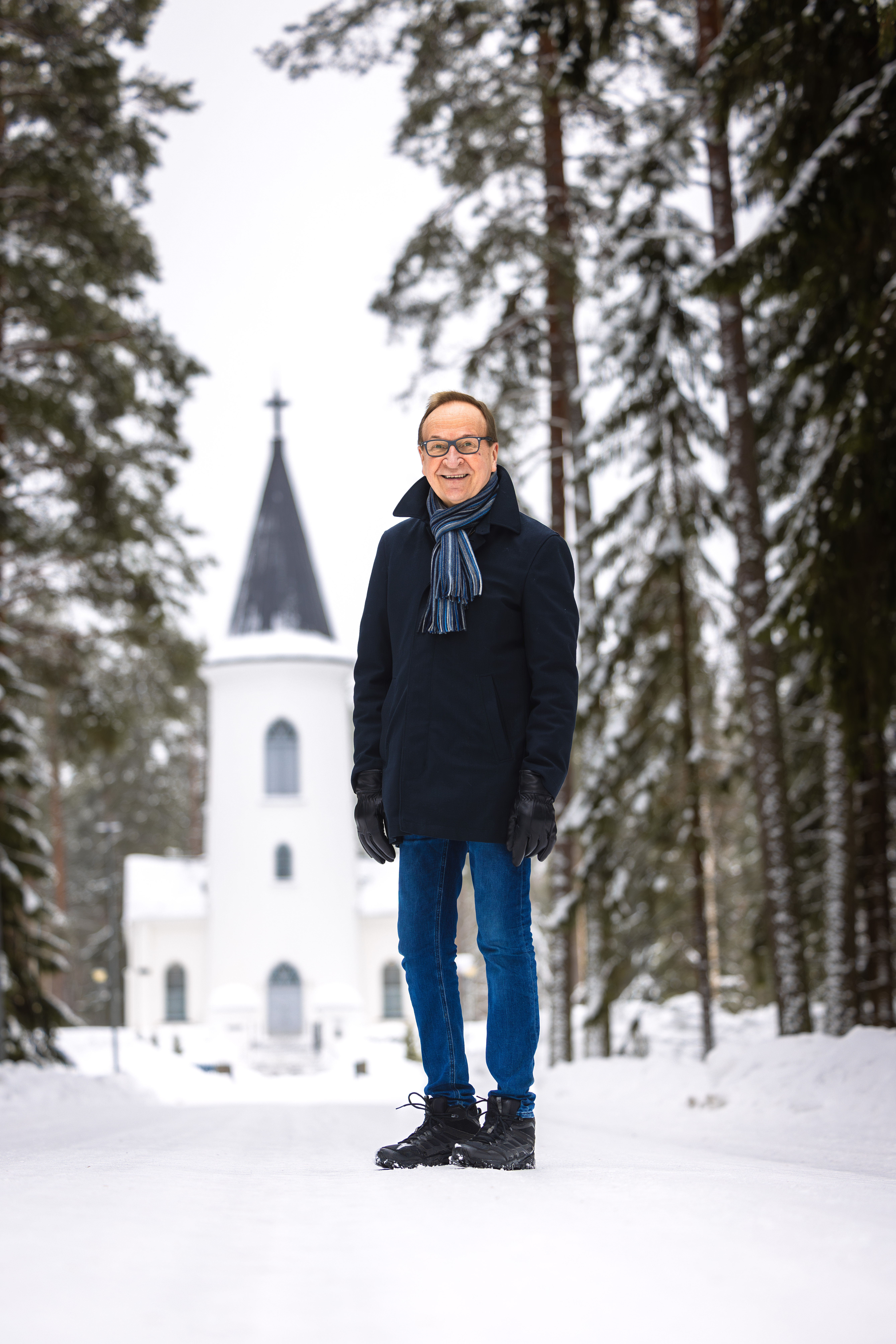 Mies seisoo lumisessa maisemassa. Takana Törnävän kirkko.