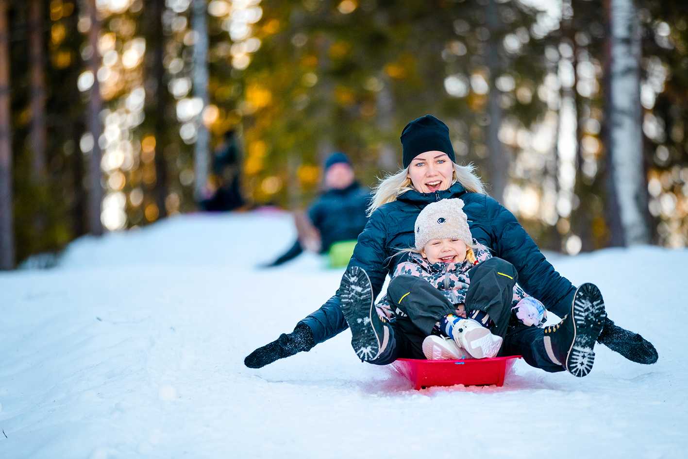 Aikuinen ja lapsi laskevat pulkalla mäkeä.