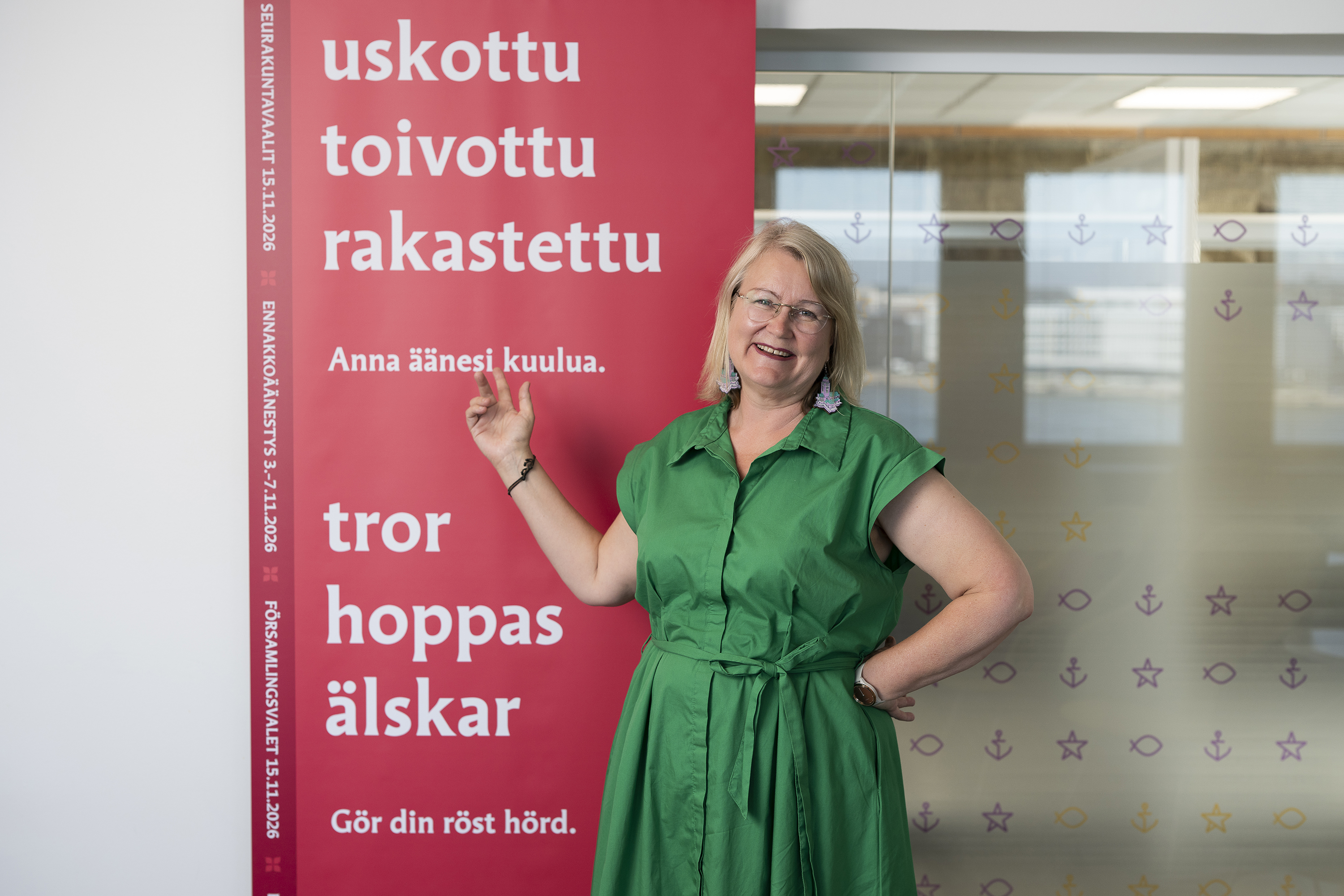 Henkilö seisoo seurakuntavaalien mainosjulisteen vierellä.