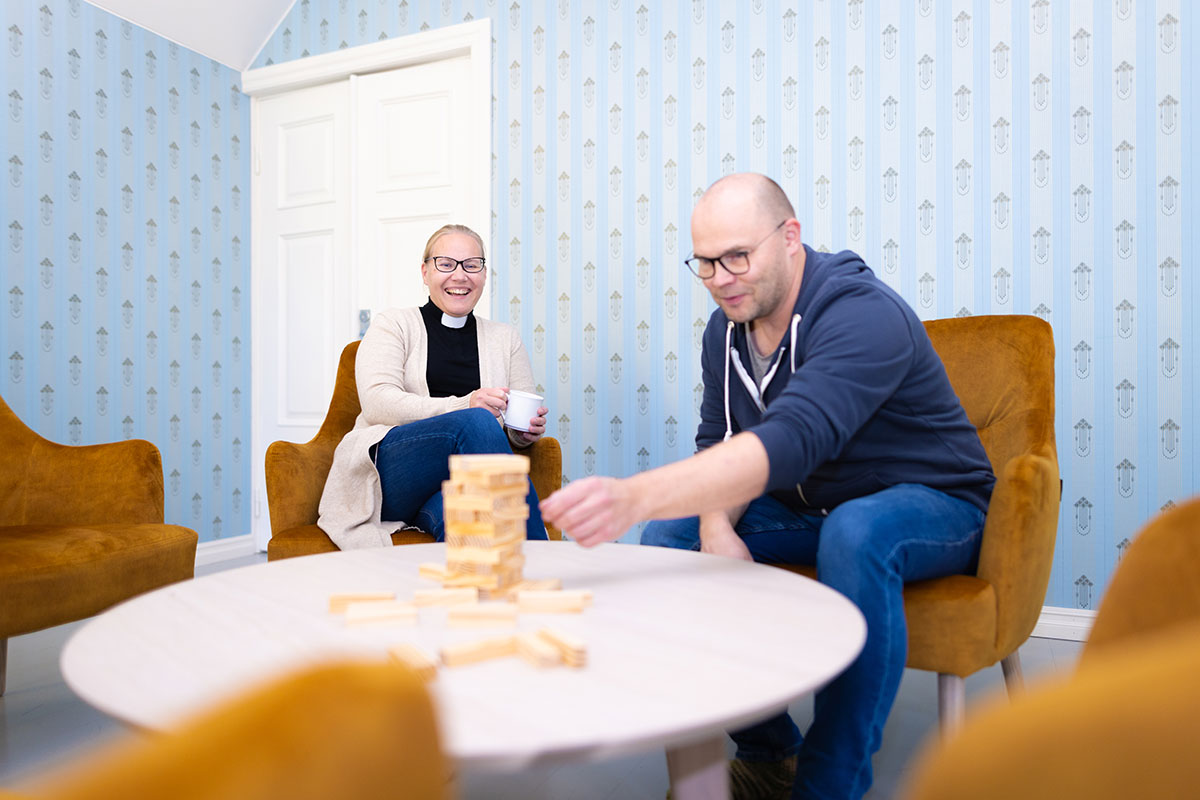 Nainen ja mies istuu hymyillen juoden kahvia ja kasaten palikoita.