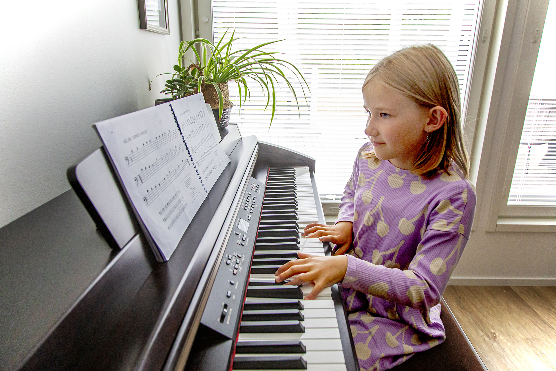 Lapsi soittaa pianoa kotonaan.