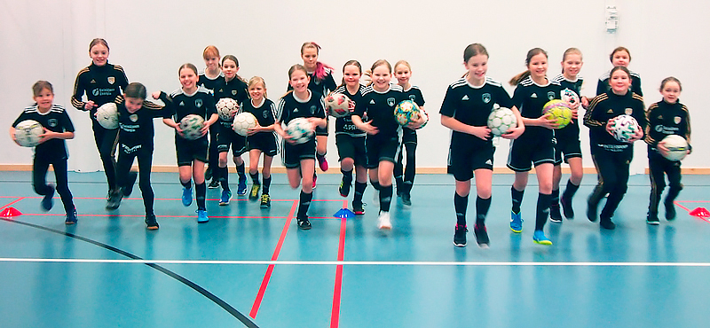 Seinäjoen Jalkapallokerhon E11-tyttöjen joukkue juoksee kameraa kohti pallot käsissään.