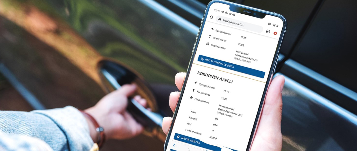 Kädessä olevassa matkapuhelimessa on avoinna Hautahaku.fi-palvelu.