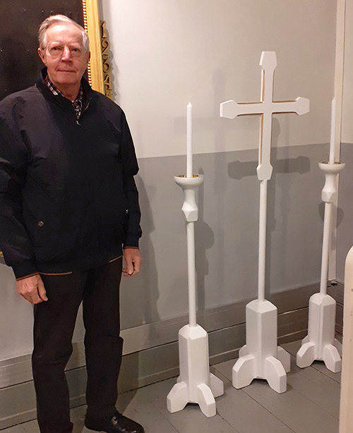 Kuvassa on Törnävän kirkkoon juuri valmistunut valkoinen kulkueristi ja kaksi kynttilää, sekä nämä työstäny...
