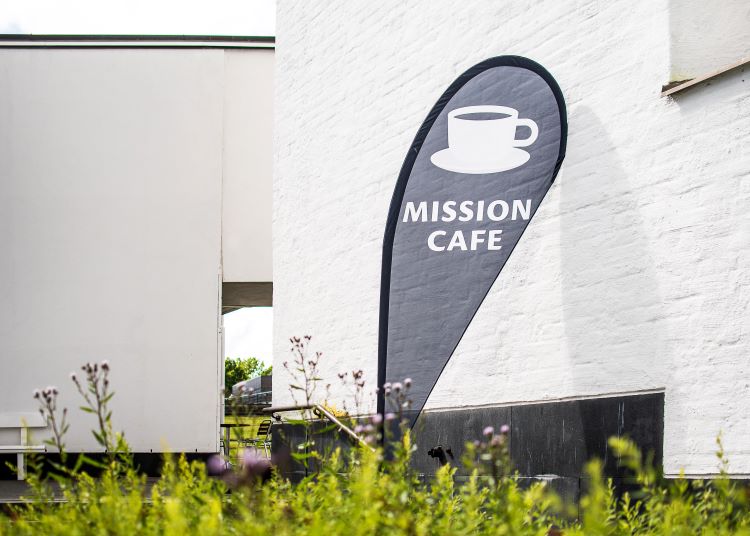 Mission Café Kahvilan banderolli kirkon seinää vasten.